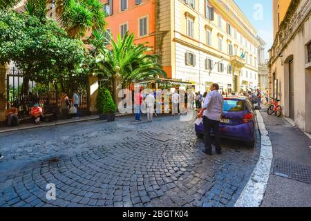 Ein Taxifahrer öffnet den Kofferraum in einer belebten Seitenstraße, die zur Kirche Saint Vicenzo auf der Piazza di Trevi in Rom führt Stockfoto