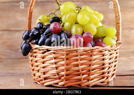 Verschiedene Arten von Trauben in Korbkorb auf Holzhintergrund Stockfoto