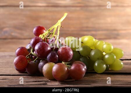 Trauben verschiedener Arten von Trauben auf Holztisch auf Holzwand Hintergrund Stockfoto