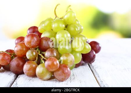 Trauben von reifen Trauben auf Holztisch auf natürlichem Hintergrund Stockfoto