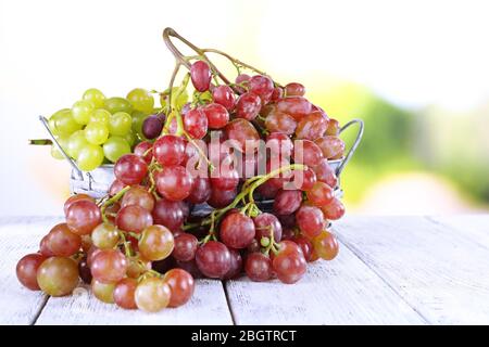 Trauben von reifen Trauben in Weidenkorb auf Holztisch auf natürlichem Hintergrund Stockfoto