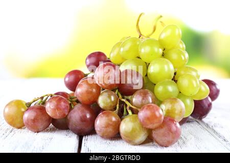 Trauben von reifen Trauben auf Holztisch auf natürlichem Hintergrund Stockfoto