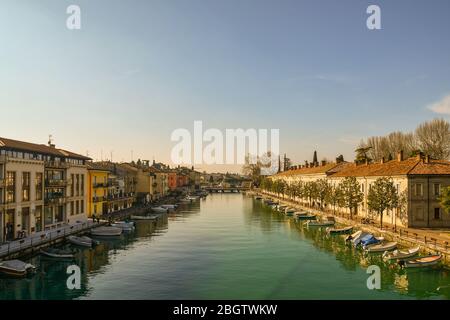 Erhöhte Ansicht des Canale di Mezzo Kanals in der Altstadt von Peschiera del Garda mit Booten vor den Ufern an einem sonnigen Tag, Verona, Venetien, Italien Stockfoto