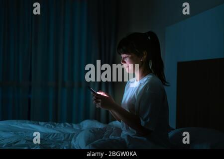 Asiatische mobile süchtig Frau mit Smartphone Surfen im Internet für Filme oder virtuelle Meeting Video-Anruf online mit Freund auf dem Bett bef Stockfoto