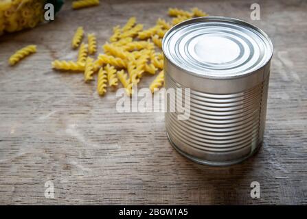 Nahrungsmittelbedarf Krise Nahrungsmittelvorrat für COVID-19 Quarantäne Isolationsperiode in gelbem Hintergrund. Verschiedene Lebensmittel in Aluminiumdosen und Pasta. Essen Stockfoto