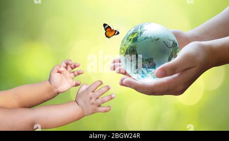 Erwachsene schicken die Welt zu Babys. Konzept Tag Erde die Welt retten Umwelt retten die Welt ist im Gras des grünen Bokeh-Hintergrundes Stockfoto