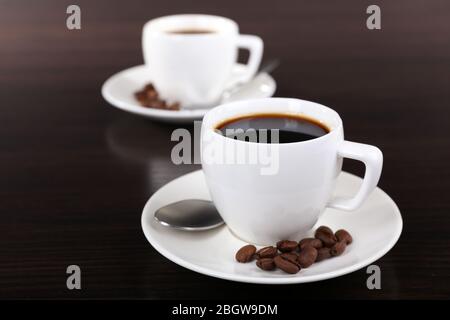 Zwei Tassen Kaffee und Kaffeebohnen auf dunklem Hintergrund Stockfoto