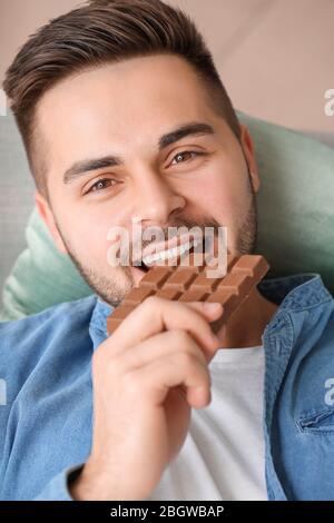 Schöner junger Mann, der zu Hause Schokolade isst Stockfoto