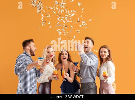 Glückliche Menschen mit Konfetti und Cocktails auf farbigen Hintergrund Stockfoto