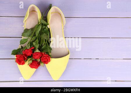 Schöne Damenschuhe mit Blumen auf Holzhintergrund Stockfoto