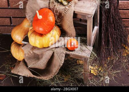 Kürbisse auf Holzleiter auf Boden auf Backstein Wand Hintergrund Stockfoto