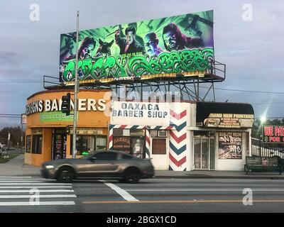 Eckläden am La Cienega Blvd. In Los Angeles mit einem Schild und Banner-Shop, mexikanischem Friseur und Plakatwand mit Graffiti in Los Angeles, CA Stockfoto