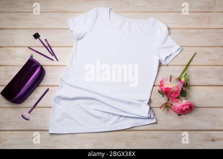 Weißes Frauen-T-Shirt-Mockup aus Baumwolle mit lila Kosmetiktasche und rosa Rosen. Design T-Shirt Vorlage, T-Print Präsentation Mock up Stockfoto