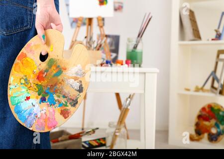Künstler hält Palette mit Farben im Kunststudio Stockfoto
