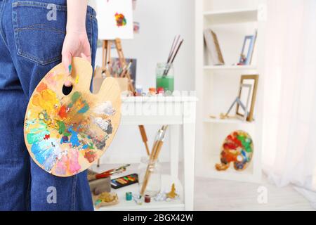 Künstler hält Palette mit Farben im Kunststudio Stockfoto
