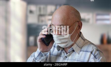 Der alte Mann spricht zu Hause am Telefon Stockfoto