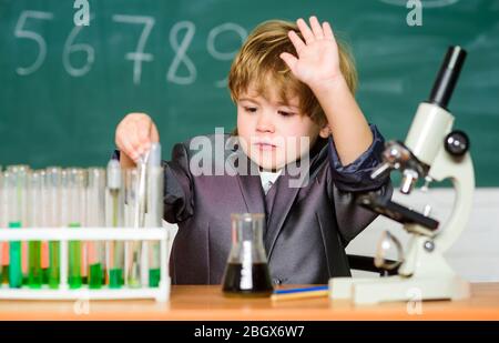 Technologie- und Wissenschaftskonzept. Kid Studium Biologie und Chemie in der Schule. Schulbildung. Untersuchen Sie biologische Moleküle. Kleinkind Genie Baby. Junge in der Nähe von Mikroskop und Reagenzgläser in der Schule Klassenzimmer. Stockfoto