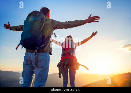 Paar mit erhobenen Armen halten die Hände und Blick auf den Sonnenuntergang Stockfoto