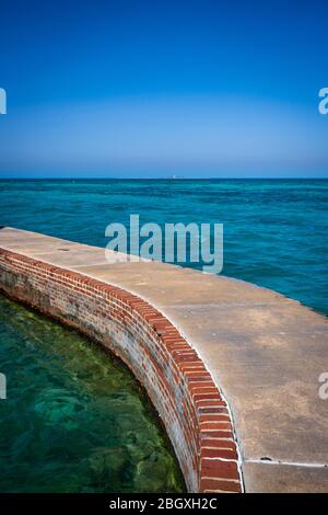 Trockene Tortugas Mote Wall mit Loggerhead Leuchtturm in der Ferne an klaren Tag Stockfoto