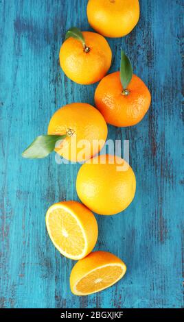 Reife Mandarinen und Orangen mit Blättern auf Holzhintergrund Stockfoto