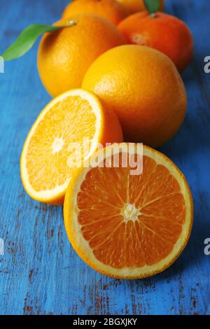 Reife Mandarinen und Orangen mit Blättern auf Holzhintergrund Stockfoto