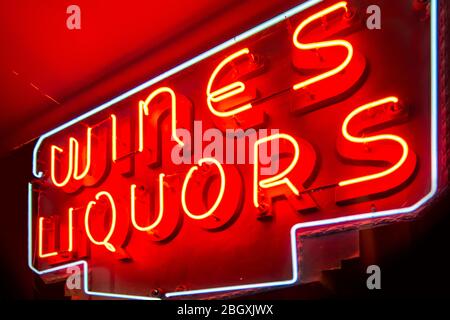 schild mit beleuchteten Neonlichtern, die Rotweine und Liköre an einer Innenwand lesen Stockfoto