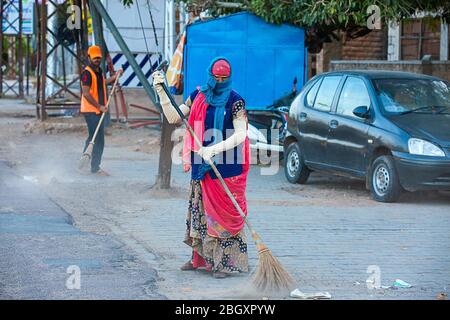 Eine Frau fegen die Straße der Stadt am Morgen manuell mit einem traditionellen Besen.Coronavirus, covid-19 Stockfoto