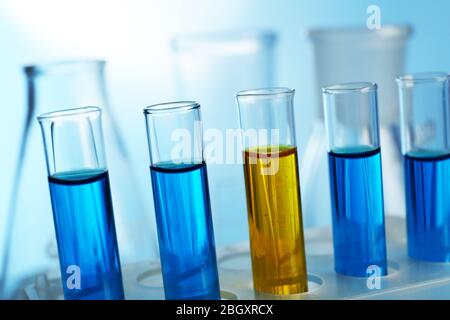 Mehrere Reagenzgläser mit farbiger Flüssigkeit mit Kolben auf hellem Hintergrund gefüllt Stockfoto
