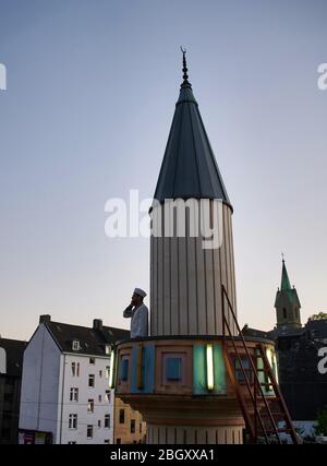 Wuppertal, Deutschland. April 2020. Mustafa Akkaya, religiöser Vertreter der Gemeinde, steht bei Sonnenuntergang auf dem Minarett der Ditib Zentralmoschee. Für die Zeit der Corona-Beschränkungen gibt es eine Ausnahme für den täglichen Muezzin-Aufruf in Wuppertal. Der Fastenmonat Ramadan beginnt unter schwierigen Umständen und großen Einschränkungen aufgrund der Corona-Pandemie. (An dpa: ' Ausnahme Ramadan: Corona-Anstrengung und kluge Ideen') Quelle: Bernd Thissen/dpa/Alamy Live News Stockfoto