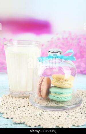 Sanfte bunte Makronen in Glas Glocke und Milchglas auf hellem Hintergrund Stockfoto