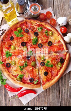 Leckere Pizza mit Wurst, Gemüse und Chili auf Holztisch Hintergrund Stockfoto