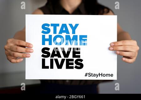 Frau mit dem Schild 'Stay Home Save Lives', globale Botschaft inmitten der Coronavirus-Krise. Quarantäne-Nachricht auf der ganzen Welt zur Bekämpfung der COVID-19-Pandemie. Stockfoto