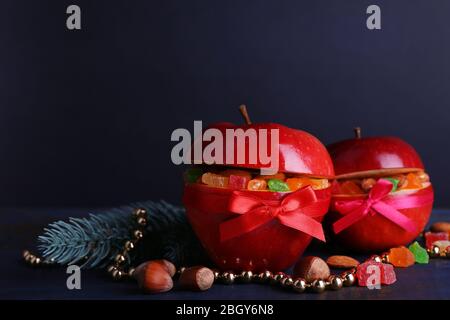 Rote Äpfel mit getrockneten Früchten auf farbigen Holztisch und dunklem Hintergrund gefüllt Stockfoto