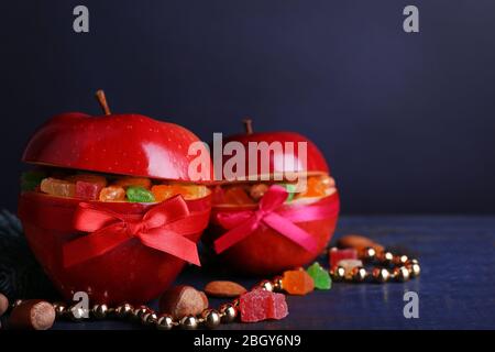 Rote Äpfel mit getrockneten Früchten auf farbigen Holztisch und dunklem Hintergrund gefüllt Stockfoto