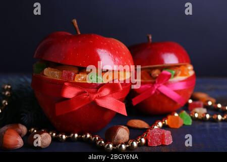 Rote Äpfel mit getrockneten Früchten auf farbigen Holztisch und dunklem Hintergrund gefüllt Stockfoto