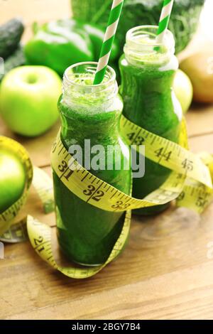 Grüner frischer gesunder Saft in Glasflaschen mit Obst und Gemüse auf Holztisch Hintergrund Stockfoto