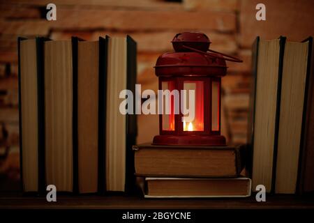 Bücher und dekorative Laterne auf Tisch und Backstein Wand Hintergrund Stockfoto