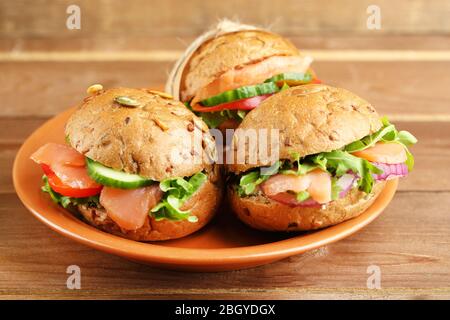 Sandwiches mit Lachs auf Teller, auf Holzhintergrund Stockfoto