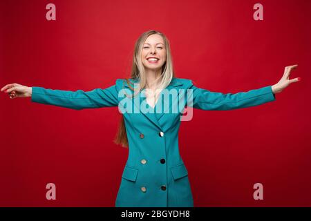 Lächelnd fröhliche blonde Frau in blauem Kleid mit ausgestreckten Kleid. Stockfoto
