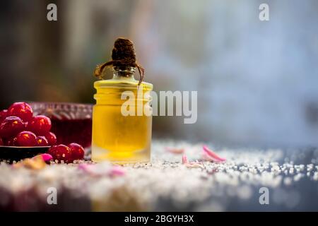 Nahaufnahme von frischen Süßkirschen oder Prunus avium mit Öl, Saft und Tee auf einer schwarz glänzenden Oberfläche mit rohen frischen Kirschen. Stockfoto