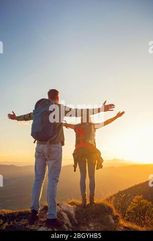 Paar mit erhobenen Armen halten die Hände und Blick auf den Sonnenuntergang Stockfoto