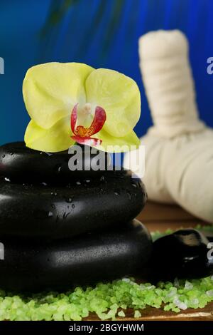 Orchideenblumen auf Spa-Steinen auf dunklem, farbenfrohem Hintergrund Stockfoto