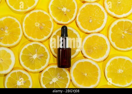 Natürliches Vitamin C Serum, Hautpflege, ätherisches Öl Produkt. Kosmetik mit frischen saftigen Zitronenfrucht-Scheibe auf Limettenhintergrund. Modell für Kosmetikprodukte. Draufsicht, flaches Lay Stockfoto