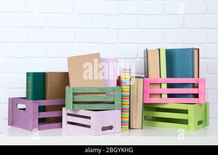 Viele Bücher in Kisten auf Backstein Wand Hintergrund Stockfoto