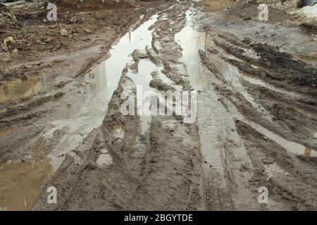 Schmutzige Feldweg mit Spur, Radspuren, brauner Lehm und Pfützen in Russland. Stockfoto
