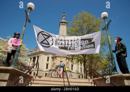 BLOOMINGTON, USA - 22. APRIL 2020: Mitglieder der Extinction Rebellion Bloomington nehmen an einer sozial fernen Erdtag Demonstration an der südöstlichen Ecke des Monroe County Courthouse Square inmitten des Coronavirus Covid-19 Ausbruch Teil. Stockfoto