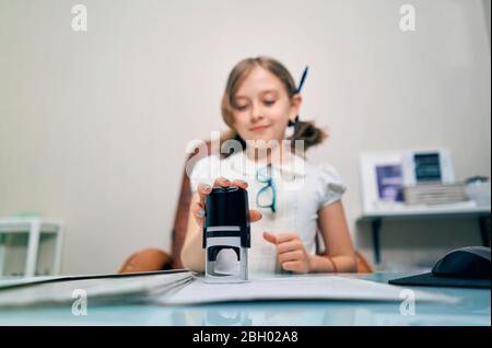 Kleines Mädchen setzt einen Stempel auf Dokumente Stockfoto