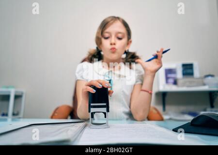 Kleines Mädchen setzt einen Stempel auf Dokumente Stockfoto