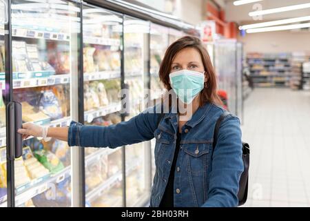 Frau trägt Einweg-medizinische Maske Einkaufen im Supermarkt Stockfoto
