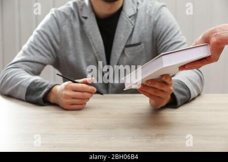 Author Signing Autograph in eigenem Buch am Holztisch auf weißem Plankenhintergrund Stockfoto